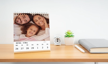 Tischkalender Fotokalender mit kleiner glücklichen Familie, Kalender steht auf Regal mit Wecker und Pflanze
