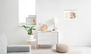 Monatskalender als Wandkalender an Wand aufgehangen, weiße Kommode mit Accessoires darunter