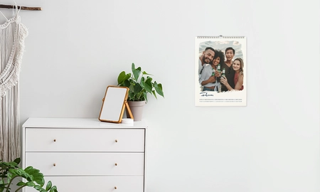 Wandkalender neben weißer Kommode, Pflanze und Spiegel auf Kommode