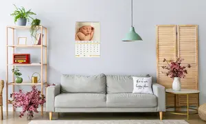 Wandkalender Monatskalender, Design mit neugeborenem Baby mit weißer Mütze, Kalender hängt über dem Sofa