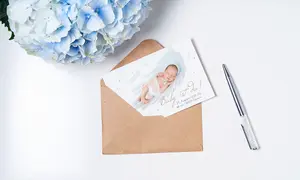 Geburtskarte mit Babyfoto und hellblauer Blume daneben