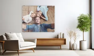 Acrylglasbild für Wohnzimmer, Mutter, Vater und Kind liegen sternförmig auf dem Boden, Wandbild hängt über Kommode