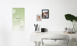 Eine Wand mit Wandkalender und gerahmten Fotos. Das Kalendarium ist grün