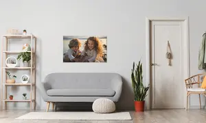 Hochwertiges Wandbild als Poster mit Kindern als Motiv hängt über Couch, daneben Pflanze