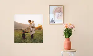 Fotoposter an rosa Wand mit Mutter und Kindern als Bild, Vordergrund kleiner Beistelltisch mit Vase und Blumen