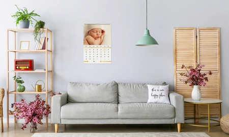 Wandkalender Monatskalender, Design mit neugeborenem Baby mit weißer Mütze, Kalender hängt über dem Sofa